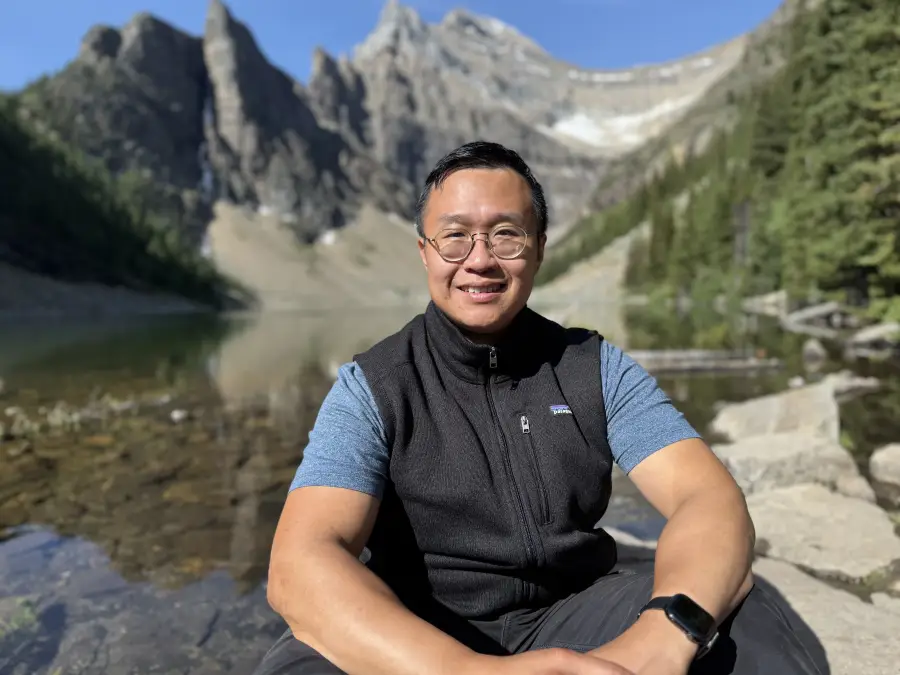 Alex Leung sitting on a mountain trail during a hiking adventure